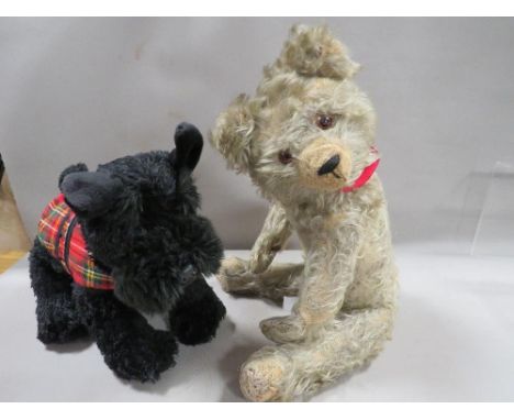 A vintage teddy bear together with a modern Scottie toy dog