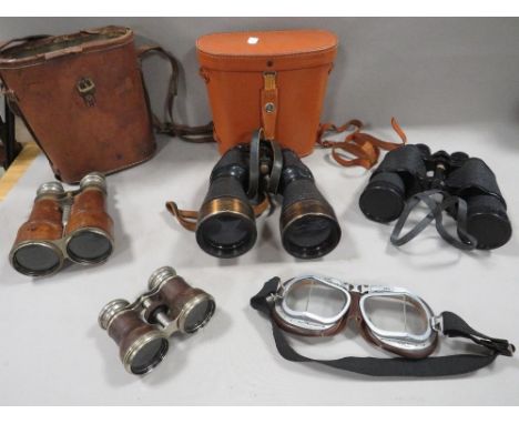 A tray of vintage binoculars together with a pair of vintage motorcycle goggles