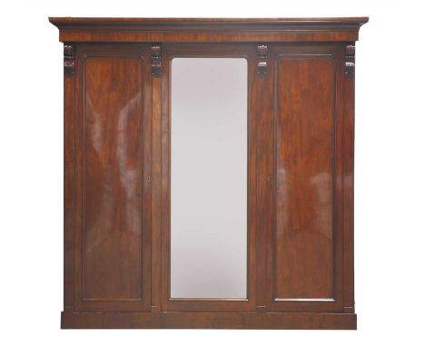 A Victorian mahogany triple wardrobe, the moulded cornice over a mirrored door, flanked by two panelled doors, 209cm wide 69c