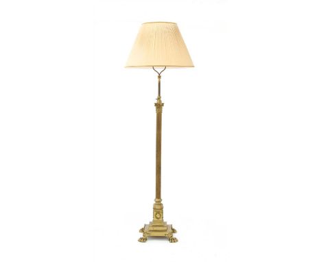 A brass Corinthian column standard lamp, with a telescopic fluted column, on a stepped square base, paw feet and a silk shade
