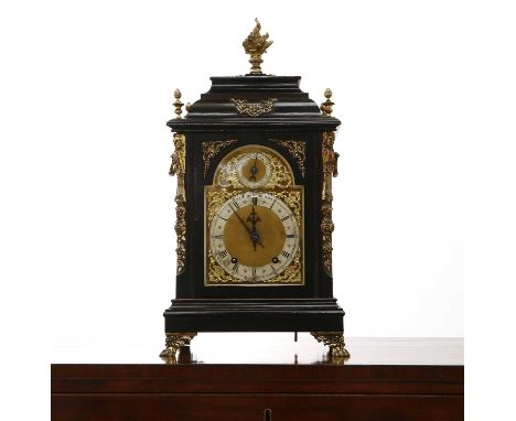 An Edwardian ebonised mantel clock, the arched brass dial with a slow/fast dial over a silvered chapter ring and scrolled spa