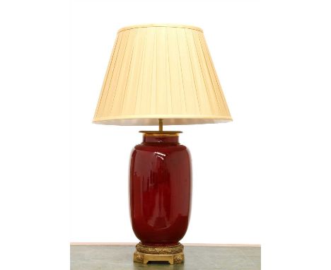 A table lamp, 20th century, the base in the form of a sang-de-boeuf vase, with cast bronze mounts and a silk shade, 75cm high