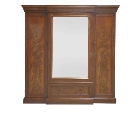 A Victorian mahogany breakfront triple wardrobe, with a moulded cornice over a central mirrored door, enclosing slides and a 