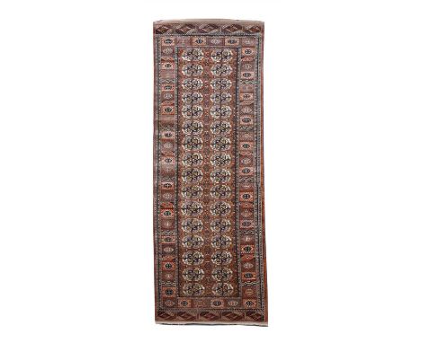A Tekke design Afghan runner, c.1990, woven on a silk foundation with geometric motifs, on shades of light madder red, 301 x 