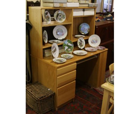 A modern computer desk with drawers and top shelf unit.