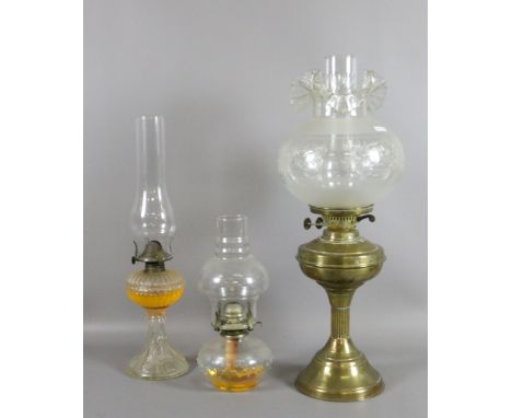 A brass based oil lamp with etched glass shade along with two pressed glass examples.