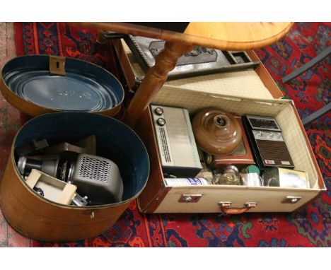 A suite case and metal hat box containing a copper bed warmer and projector, along with transistor radios horse brasses and o