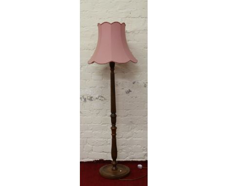 A carved and reeded mahogany standard lamp with pink shade.