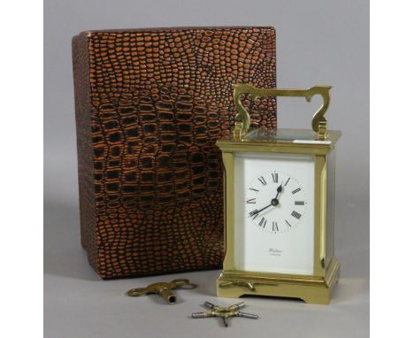A boxed brass cased carriage clock by Huber London with white enamel dial and Roman numeral markers and keys.