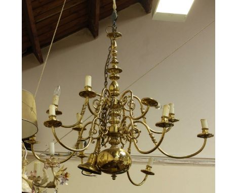 A large brass twelve light chandelier, with scrolling branches and a turned central column