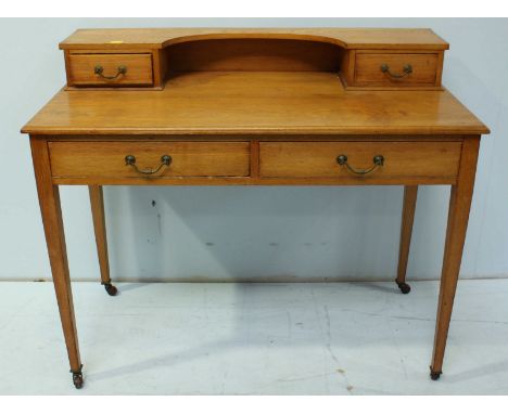 An Edwardian oak writing desk, the upper section fitted with two drawers and curved shelf, over two further drawers and suppo