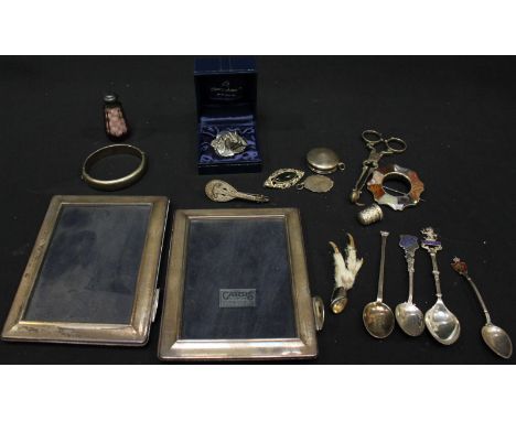 A small collection of assorted silver objects d'art including a bangle, brooches, scent bottle, sugar nips, tea spoon, and a 