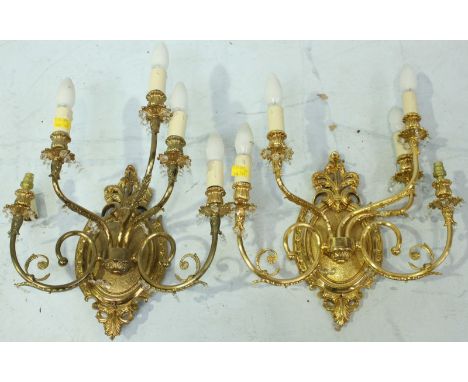 A pair of five light gilt metal wall lights, with shield shaped crested centres and scrolling arms