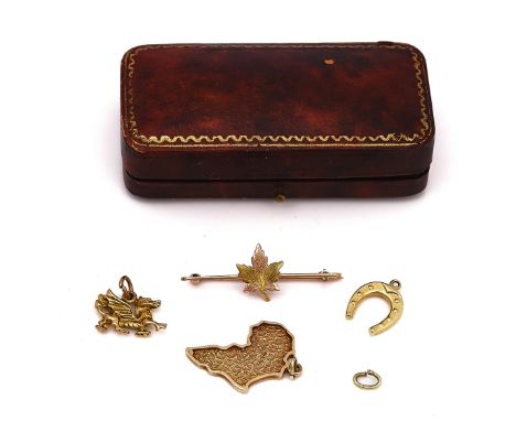 THREE GOLD CHARMS AND A GOLD BROOCH (4)The charms comprising; a 9ct gold Welsh dragon, a map of Africa, detailed 9 CT and a h