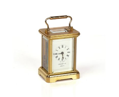 A SMALL BRASS CARRIAGE TIMEPIECELate 20th CenturyThe white dial with Roman numerals and signed Garrard &amp; Co, with a fitte