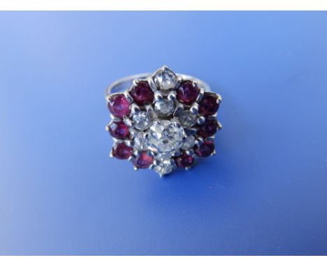 A modern ruby & diamond cluster ring, the old cut central diamond weighing approximately 0.60 carat in 18ct white metal.
