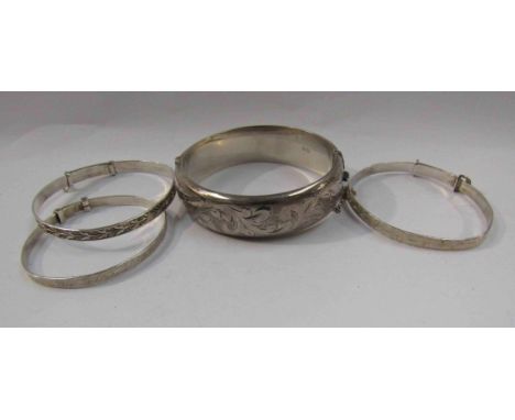 A silver wax filled engraved stiff hinge bangle, two silver christening bracelets and another stamped sterling, 64.6g    