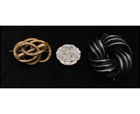 A Victorian pinchbeck brooch in the form of a knot together with a jet brooch (repaired) and a large Czech Art Nouveau metal 
