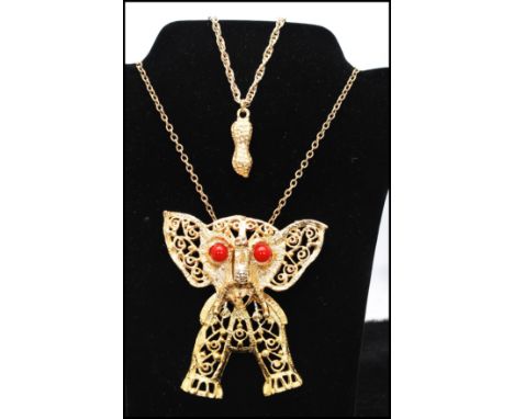 A vintage Delizza and Elster large articulated elephant pendant necklace having coral coloured eyes together with a gold tone