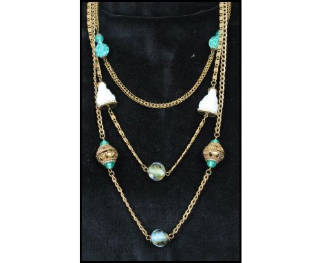 A signed vintage Miriam Haskell gold tone three strand necklace strung with white glass buddhas with green and marbled glass 