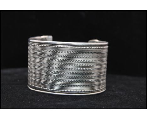 A vintage white metal cuff bangle having filigree decoration. Width approx 4cm. Weight 43.g