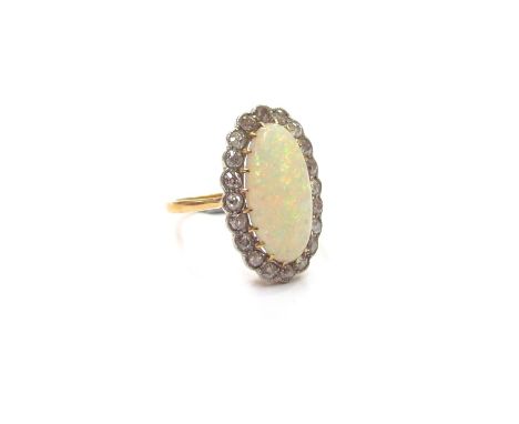 An 18ct gold platinum set opal and diamond ring, the central oval opal 15mm x 8mm framed by diamonds. Size K/L, 4.2g 