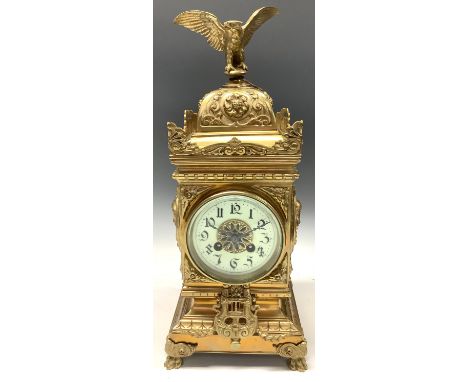A 19th century brass mantel clock, the case embossed with masks and scrolls, eagle finial, Arabic numerals, twin winding hole