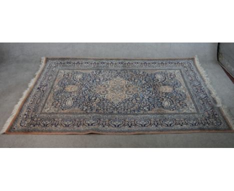 A 20th century green ground Persian carpet, the central diamond lozenge surrounded by floral scroll decoration. W.148 L.242cm