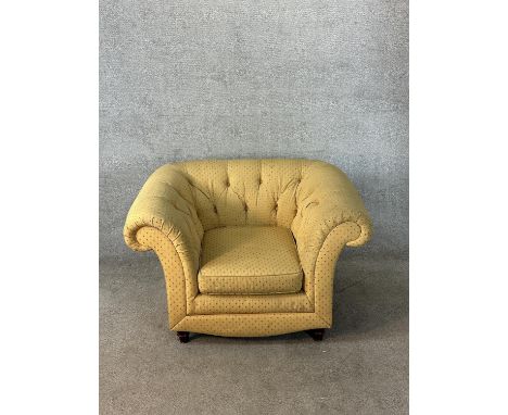 A 19th century button back scroll arm deep seated yellow upholstered armchair raised on turned supports. H.90cm 