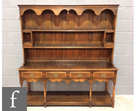 A reproduction oak dresser in the 18th Century style, the upright two-tier plate rack section with a shaped cornice over alco