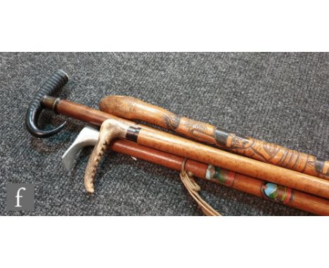 A Japanese bamboo walking stick carved with warriors, another with and aluminium pick axe handle and two horn ended examples.