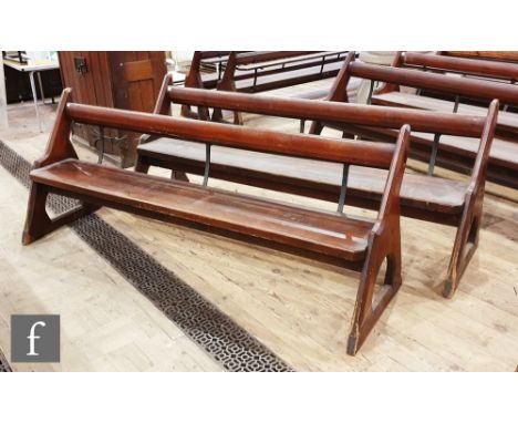 A pair of stained pine pews each with iron bar supports and book shelf on shaped open ends, height 88cm x depth 67cm x length