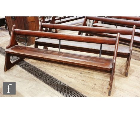 A pair of stained pine pews each with iron bar supports and book shelf on shaped open ends, height 88cm x depth 67cm x length