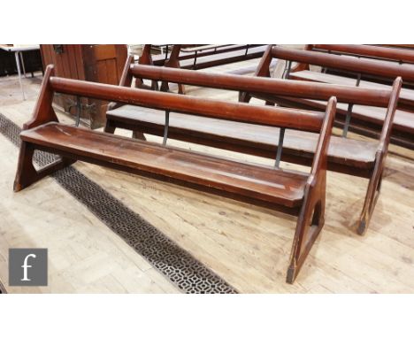 A pair of stained pine pews each with iron bar supports and book shelf on shaped open ends, height 88cm x depth 67cm x length
