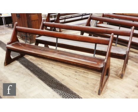 A pair of stained pine pews each with iron bar supports and book shelf on shaped open ends, height 88cm x depth 67cm x length