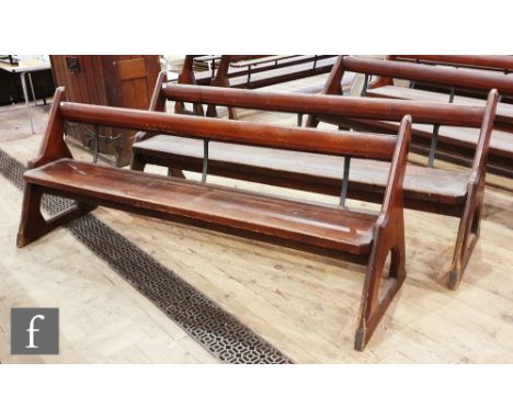 A pair of stained pine pews each with iron bar supports and book shelf on shaped open ends, height 88cm x depth 67cm x length
