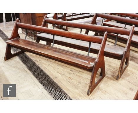 A pair of stained pine pews each with iron bar supports and book shelf on shaped open ends, height 88cm x depth 67cm x length
