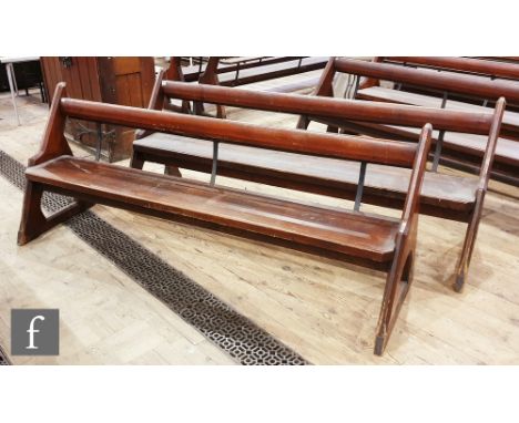 A pair of stained pine pews each with iron bar supports and book shelf on shaped open ends, height 88cm x depth 67cm x length