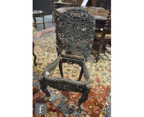 A late 19th Century Anglo Burmese hardwood standard chair, with profusely fret-carved foliate detail and with mask mounts, la