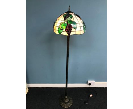 A Tiffany style standard lamp. Ornately designed with grapes and vines. Working. Measures 162cm in height 