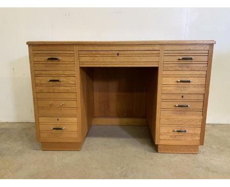 A mid century light oak pedestal desk with large central drawer flanked by four pedestal drawers. W:118cm x D:57cm x H:79cm