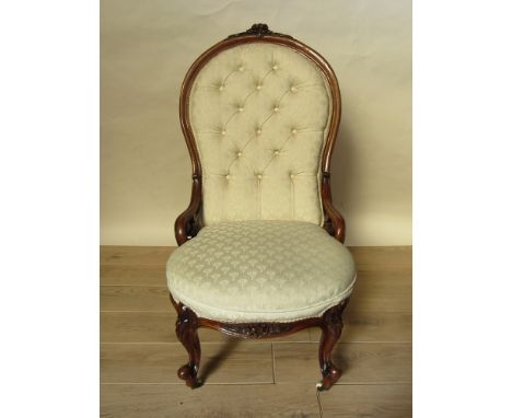 Circa 1840 a walnut open armchair, the carved floral crested spoon back with buttoning over a bow front seat and pierced scro