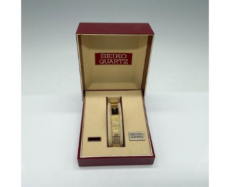 Gold-toned watch with a black face featuring a diamond at the 12 o'clock position. This item has its original box which measu