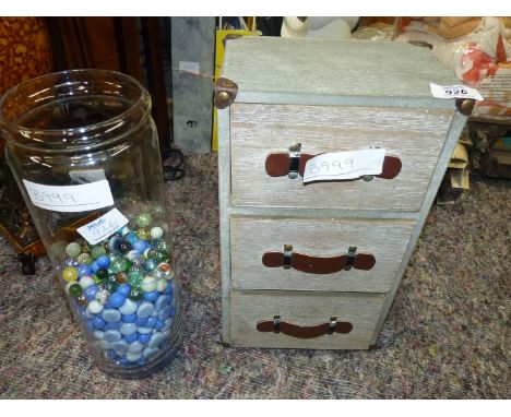 A jar of marbles and a small three drawer filing cabinet.