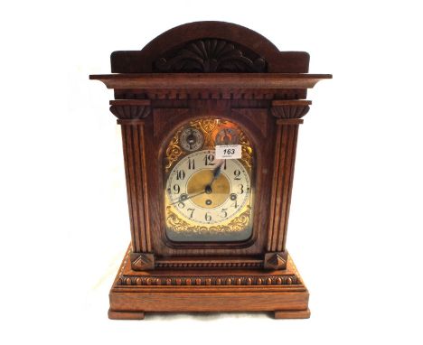 A German carved Oak striking mantel clock with silvered and gilt dial with silent chime