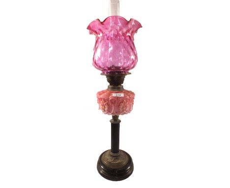 A Victorian oil lamp with pink opal glass bowl and cranberry shade