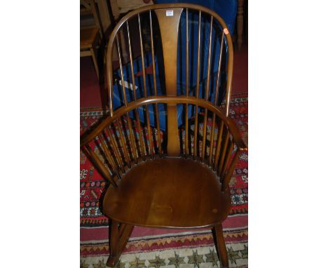 An Ercol dark elm stickback Windsor rocking chair; together with two Ercol dark elm stickback kitchen chairs; and one other E