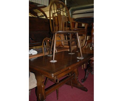 An Ercol dark elm draw-leaf dining table, together with a set of four Ercol dark elm splatback dining chairs (5)