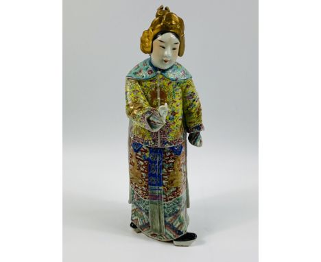A Chinese porcelain figure of an attendant, richly enamelled and decorated throughout with vibrant colours, applied square se