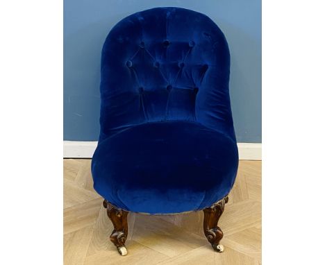 A small Victorian boudoir chair with buttoned upholstery and raised upon carved walnut cabriole legs with ceramic castors, 47